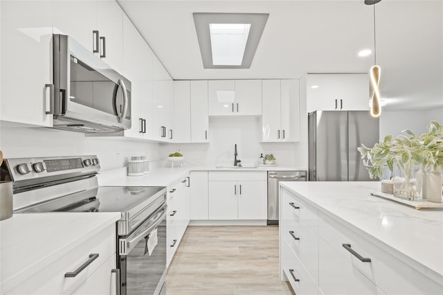 kitchen with white cabinets, sink, decorative light fixtures, light hardwood / wood-style floors, and stainless steel appliances