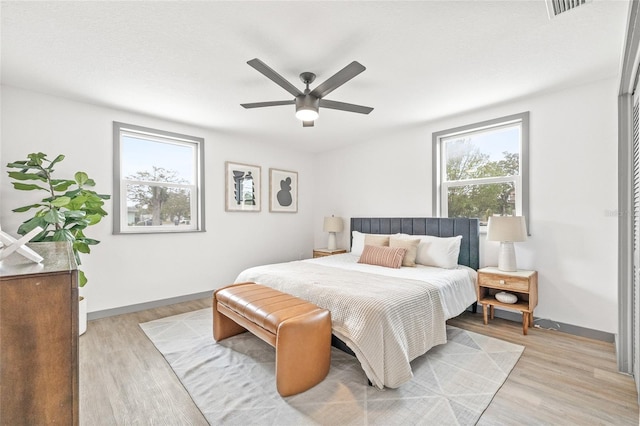 bedroom with light wood-type flooring, multiple windows, and ceiling fan