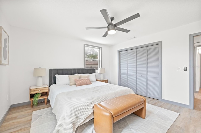 bedroom with ceiling fan, light hardwood / wood-style floors, and a closet