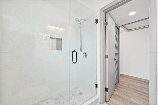 bathroom with a shower with shower door and hardwood / wood-style flooring