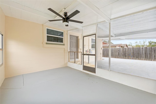 unfurnished sunroom with beamed ceiling, ceiling fan, and a healthy amount of sunlight