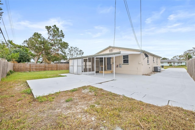 rear view of house featuring a sunroom, a yard, a patio, and central AC unit