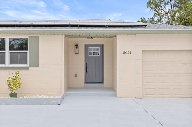 view of exterior entry featuring solar panels and a garage