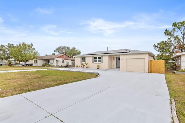 ranch-style home featuring a front yard, solar panels, and a garage