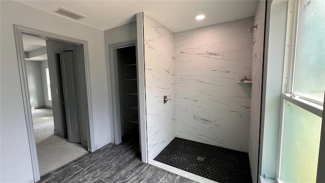 bathroom with a spacious closet, visible vents, a shower stall, and wood finished floors