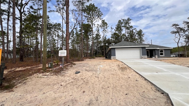 exterior space with an attached garage, stone siding, and driveway