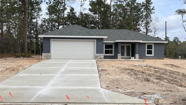 ranch-style house featuring a garage, french doors, stone siding, and stucco siding