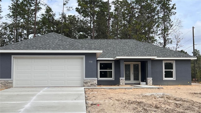 view of front of property featuring a garage, stone siding, roof with shingles, and stucco siding