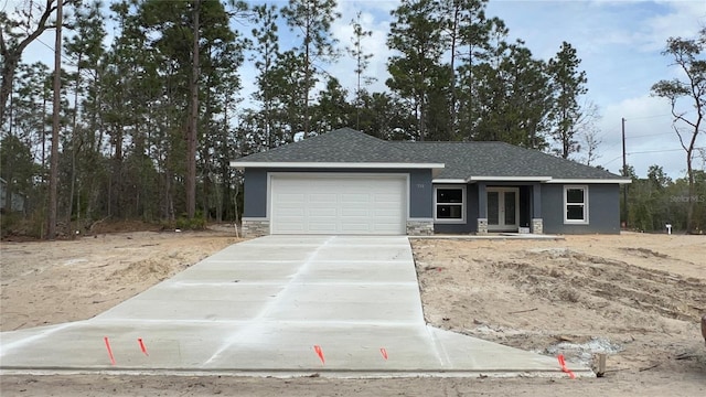 view of front of house with stucco siding, a shingled roof, a garage, stone siding, and driveway