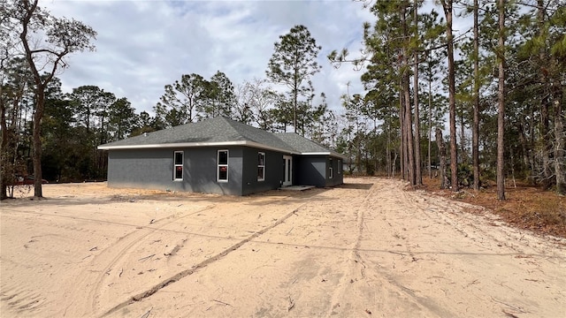 exterior space featuring roof with shingles and stucco siding