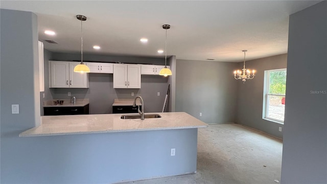 kitchen with white cabinets, light stone counters, a peninsula, pendant lighting, and a sink