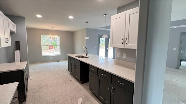 kitchen featuring dark cabinets, hanging light fixtures, a sink, white cabinetry, and a wealth of natural light