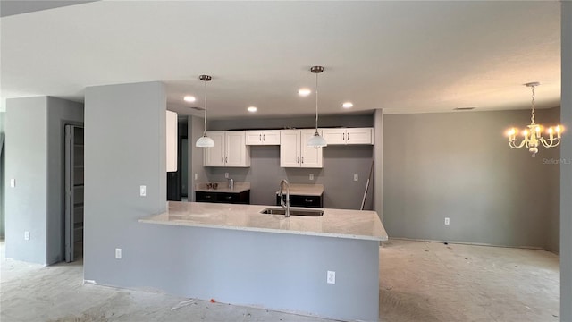 kitchen with light stone counters, hanging light fixtures, a peninsula, white cabinetry, and a sink