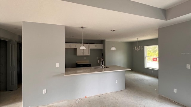 kitchen featuring light countertops, white cabinets, a sink, concrete flooring, and a peninsula