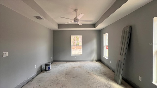 spare room featuring ceiling fan, a tray ceiling, visible vents, and baseboards