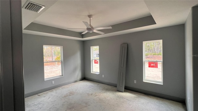 unfurnished room featuring a wealth of natural light, a raised ceiling, visible vents, and baseboards