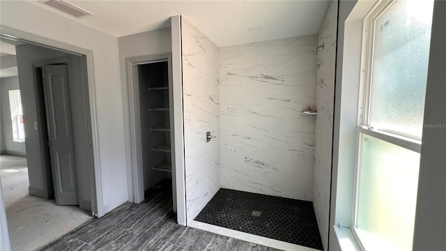 bathroom featuring a shower stall, a spacious closet, visible vents, and wood finished floors