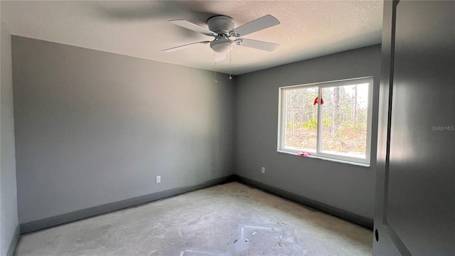 unfurnished room with ceiling fan, concrete floors, baseboards, and a textured ceiling