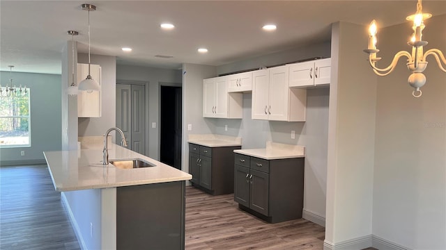 kitchen featuring wood finished floors, a sink, a peninsula, and an inviting chandelier