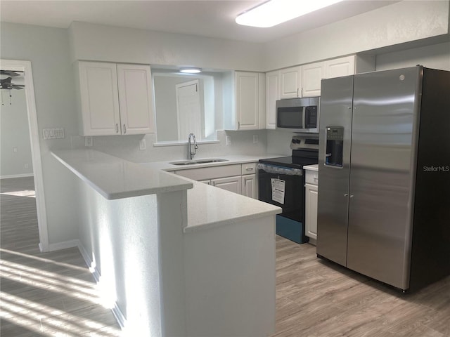 kitchen with sink, white cabinets, stainless steel appliances, and light wood-type flooring