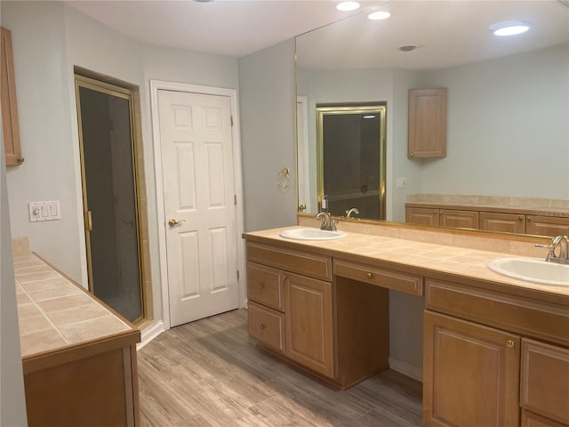 bathroom with wood-type flooring, vanity, and a shower with shower door