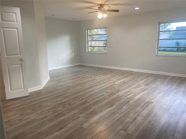 unfurnished room featuring plenty of natural light, dark wood-type flooring, and ceiling fan