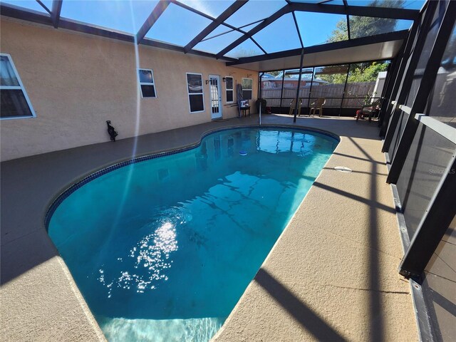 view of swimming pool with a fenced in pool, glass enclosure, fence, and a patio