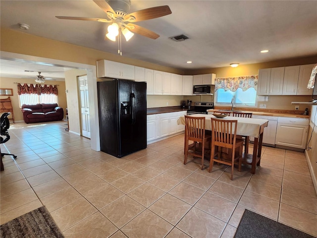 kitchen with light tile patterned floors, open floor plan, white cabinetry, a sink, and black appliances