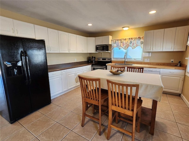 kitchen featuring light tile patterned floors, stainless steel appliances, a sink, and white cabinetry