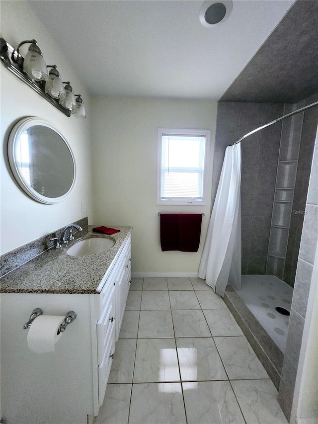 full bath with marble finish floor, tiled shower, vanity, and baseboards