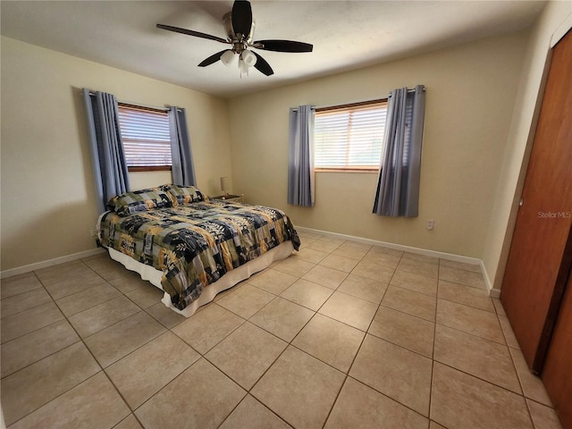 bedroom featuring multiple windows, baseboards, a ceiling fan, and light tile patterned flooring