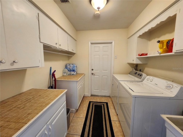 laundry room with light tile patterned floors, cabinet space, visible vents, a sink, and independent washer and dryer