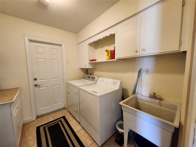 laundry area featuring washer and clothes dryer, light tile patterned flooring, a sink, and cabinet space