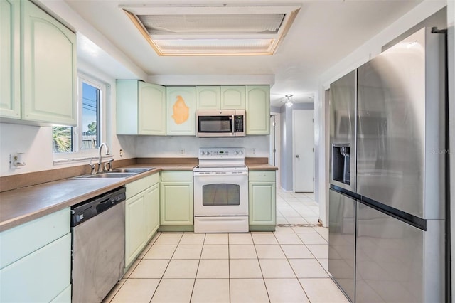 kitchen with green cabinets, light tile patterned flooring, sink, and appliances with stainless steel finishes