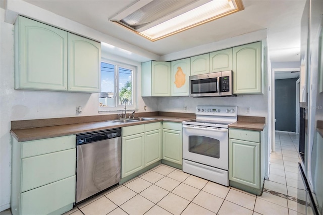 kitchen with sink, light tile patterned floors, stainless steel appliances, and green cabinetry