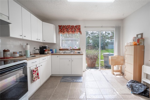 kitchen with backsplash, electric stove, white cabinetry, and a textured ceiling