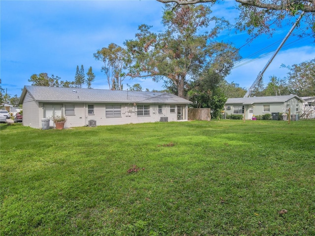 rear view of property featuring central AC and a lawn