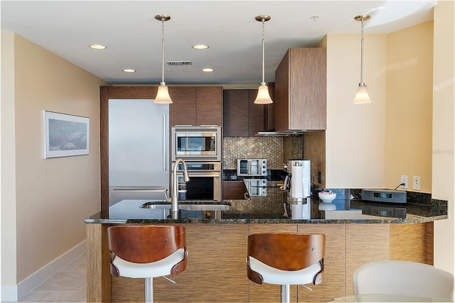 kitchen featuring stainless steel appliances, dark stone counters, and sink