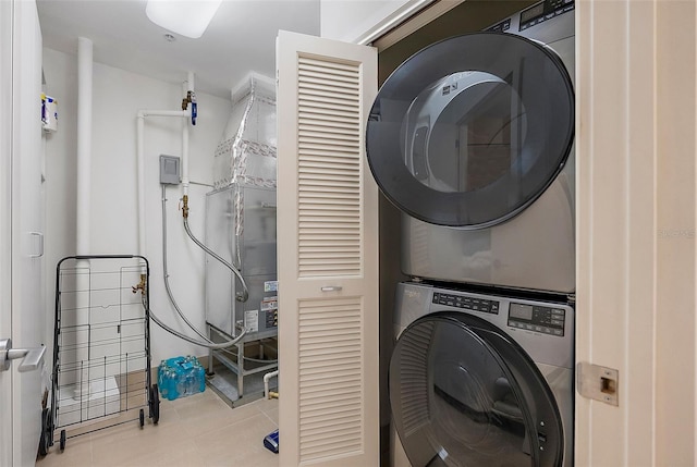 clothes washing area featuring light tile patterned floors and stacked washer and clothes dryer