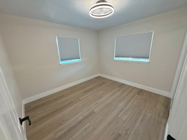 unfurnished room featuring light hardwood / wood-style floors and a textured ceiling