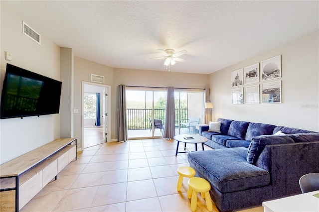 tiled living room featuring ceiling fan and a textured ceiling