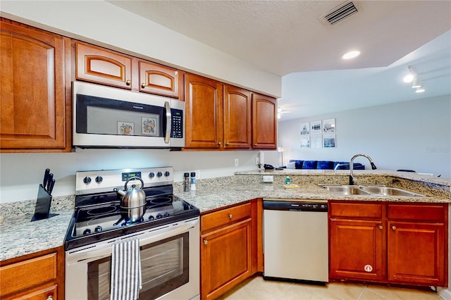 kitchen with sink, light stone countertops, light tile patterned floors, appliances with stainless steel finishes, and kitchen peninsula