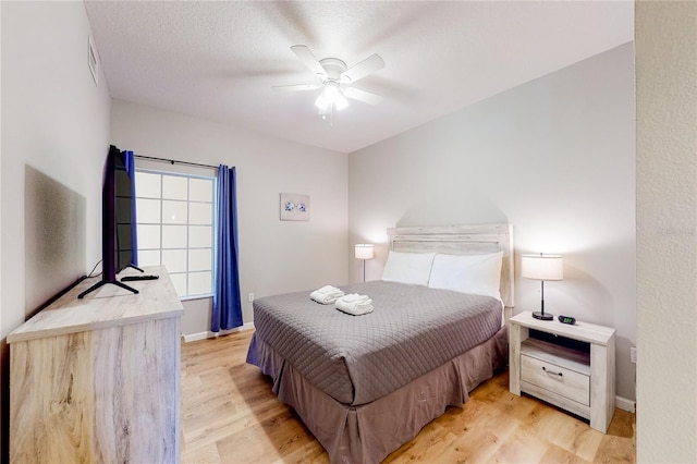 bedroom featuring ceiling fan, light wood-type flooring, and a textured ceiling