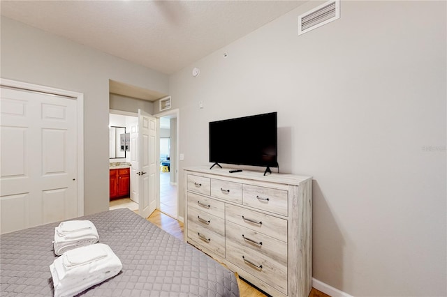 bedroom with light wood-type flooring and ensuite bath