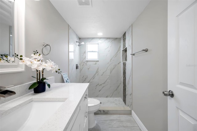 bathroom featuring vanity, toilet, and a tile shower