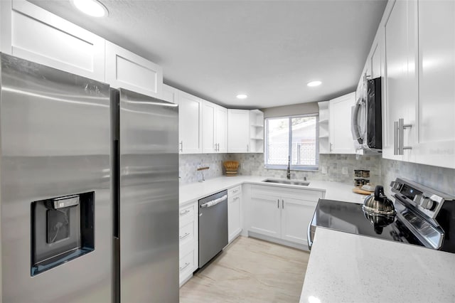 kitchen featuring light stone countertops, sink, stainless steel appliances, decorative backsplash, and white cabinets