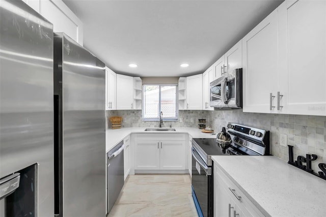 kitchen with white cabinets, sink, tasteful backsplash, light stone counters, and stainless steel appliances