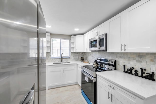 kitchen featuring backsplash, sink, white cabinetry, and stainless steel appliances