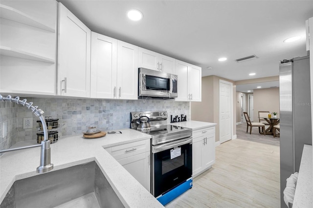 kitchen with white cabinetry, sink, backsplash, appliances with stainless steel finishes, and light wood-type flooring