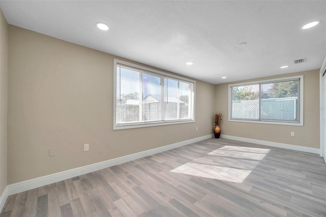 empty room featuring a healthy amount of sunlight and light hardwood / wood-style floors